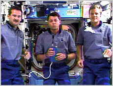 From left to right, STS-100 Mission Specialist Chris Hadfield, Pilot Jeff Ashby and Mission Specialist Scott Parazynski participate in interviews with CNN, CBS News and Fox News from inside the International Space Station. The white object in front of Parazynski is a model space shuttle. NASA image.