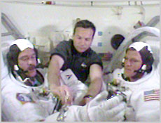 STS-100 Mission Specialists Chris Hadfield (left) and Scott Parazynski suit up in preparation for today's space walk. Mission Specialist Yuri Lonchakov assists the two space walkers in the shuttle's airlock. NASA image.