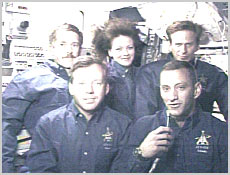 The STS-104 crew talk to journalists on Earth after undocking from the International Space Station. In front, from left, are Commander Steve Lindsey and Pilot Charles Hobaugh. In back, from left, are Mission Specialists James Reilly, Janet Kavandi and Michael Gernhardt. NASA image