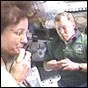 STS-108 Mission Specialist Linda Godwin and Commander Dom Gorie share a snack inside Space Shuttle Endeavour's flight deck. NASA image.