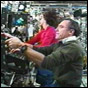 NASA image of STS-110 Mission Specialist Ellen Ochoa, in the background, and Expedition Four Flight Engineer Carl Walz, operating the Space Station's robotic arm during EVA2. Click for a larger (but slightly different) image.