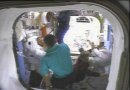 Piers Sellers (left) talks to ISS Commander Valery Korzun (back to camera). Fyodor Yurchikhin floats above while Pam Melroy assists Dave Wolf (right) with his spacesuit after EVA #3. NASA TV capture.
