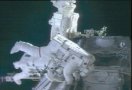 David Wolf (foreground) and Piers Sellers (background) float outside the International Space Station. NASA TV capture.