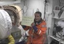 Mission Specialist Charlie Camarda holds up a note to family members while inside the White Room. NASA Image.