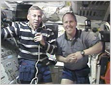 From the shuttle's flight deck, Commander Kenneth Cockrell and Mission Specialist Thomas Jones talk with reporters on Earth about the objective of the STS-98 mission. Image courtesy of NASA.